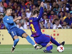 FC Barcelona's Gerard Pique, right, duels for the ball against Real Madrid's Cristiano Ronaldo during the Spanish Supercup, first leg, soccer match between FC Barcelona and Real Madrid at the Camp Nou stadium in Barcelona, Spain, Sunday, Aug. 13, 2017. (AP Photo/Manu Fernandez)