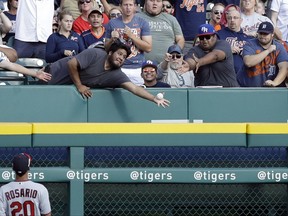 A baseball fan reaches for the grand slam hit by Detroit Tigers' James McCann during the first inning of a baseball game against the Minnesota Twins, Saturday, Aug. 12, 2017, in Detroit. (AP Photo/Carlos Osorio)