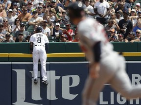 Minnesota Twins designated hitter Robbie Grossman rounds second Detroit Tigers left fielder Justin Upton (8) watches as the two-run home run by Miguel Sano clears the wall during the third inning of a baseball game, Sunday, Aug. 13, 2017, in Detroit. (AP Photo/Carlos Osorio)