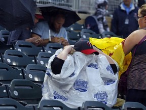 A Twins cap emerges as a fan puts on a rain cover during a rain delay prior to a baseball game between the Minnesota Twins and the Cleveland Indians on Wednesday, Aug. 16, 2017, in Minneapolis. (AP Photo/Jim Mone)