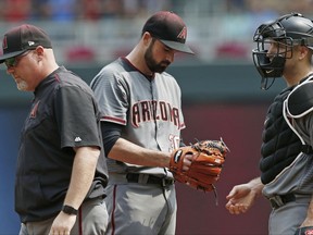 Arizona Diamondbacks pitcher T.J. McFarland, center, stands quietly after a visit to the mound by pitching coach Mike Butcher, left, in the first inning of a baseball game against the Minnesota Twins, Sunday, Aug. 20, 2017, in Minneapolis. McFarland left the game in the first after giving up five runs. (AP Photo/Jim Mone)