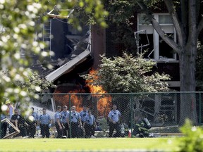 Emergency personnel move away as a gas fire continues to burn following an explosion at Minnehaha Academy Wednesday, Aug. 2, 2017, in Minneapolis. Several people are unaccounted for after an explosion and partial building collapse Wednesday at a Minneapolis school, fire officials said.  (David Joles/Star Tribune via AP)