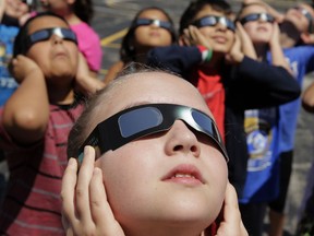 In this photo taken Friday, Aug. 18, 2017, fourth graders at Clardy Elementary School in Kansas City, Mo. practice the proper use of their eclipse glasses in anticipation of Monday's solar eclipse.  One man who took in an eclipse without the protective eyewear is warning others to listen to the experts and avoid the temptation to look up.