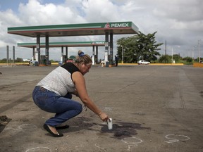 A woman places a candle on the ground at the gas station where the reporter of the Diario de Acayucan, Candido Rios Vazquez, was murdered in Hueyapan de Ocampo, Veracruz state, Mexico, Wednesday, Aug. 23, 2017. The National Human Rights Commission said that Rios was the ninth journalist slain so far this year in Mexico. Rios reportedly had been threatened repeatedly since 2012 by a former mayor of Hueyapan de Ocampo. (AP Photo/Felix Marquez)