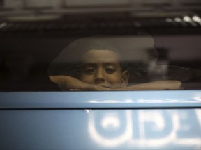 A boy looks out the window of a private bus used by Mexican authorities to transport a large group of Central American migrants to a migrant detention facility in Veracruz, Mexico, late Saturday, Aug. 19, 2017. Authorities say they rescued at least 115 migrants in Veracruz, a Mexican state located along the traditional route Central American migrants take to the U.S. Local press reports the group was being transported in inhumane conditions in a trailer. (AP Photo/Felix Marquez)
