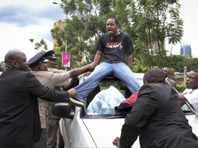 FILE - In this Wednesday, May 1, 2013 file photo, Boniface Mwangi, center, is arrested by security forces while staging a protest during Labor Day celebrations at Uhuru Park in downtown Nairobi, Kenya. Appalled by government corruption, Mwangi decided to put down his camera and become a political activist but is now reinventing himself again, campaigning for a seat in Kenya's parliament to represent one of Nairobi's impoverished neighborhoods. (AP Photo/File)