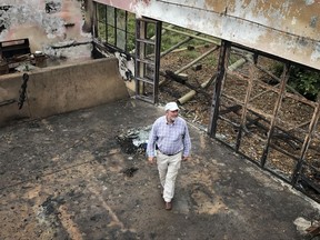In this photo taken Thursday, July 27, 2017, farmer Martin Evans inspects a blackened home, burned down during an invasion by semi-nomadic herders on his property in Laikipia, Kenya. Farms and houses here have been under siege by semi-nomadic herders and burned-out homes in this dry landscape have become a symbol of the tensions around the presidential election on Aug. 8 as Kenyans prepare for the possibility of yet more deadly violence. (AP Photo/Joe Mwihia)
