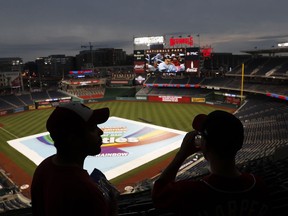 Daniel Baker, left, and Taylor Triggs, of Arlington, Va., wait under the concourse during a rain delay of a baseball game between the San Francisco Giants and the Washington Nationals, Friday, Aug. 11, 2017, in Washington. (AP Photo/Carolyn Kaster)