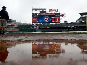 A member of the grounds crew waits to remove the tarp from the field as rain stops before a baseball game between the Miami Marlins and the Washington Nationals, Monday, Aug. 7, 2017, in Washington. (AP Photo/Carolyn Kaster)