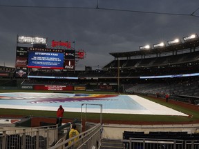 A screen directs fans to take cover under the concourse as a storm approaches and a tarp covers the field during a rain delay of a baseball game between the San Francisco Giants and the Washington Nationals, Friday, Aug. 11, 2017, in Washington. (AP Photo/Carolyn Kaster)