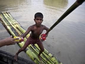 A flood affected boy on a makeshift banana raft collects biscuit packets distributed by a government official from a boat in Pokoria village, east of Gauhati, north eastern Assam state, India, Monday, Aug. 14, 2017. Heavy monsoon rains have unleashed landslides and floods that killed dozens of people in recent days and displaced millions more across northern India, southern Nepal and Bangladesh. (AP Photo/Anupam Nath)