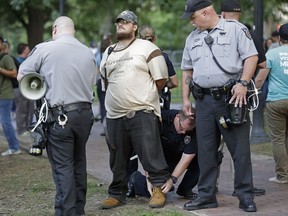 Police arrest a man during a protest at a Confederate monument at the University of North Carolina in Chapel Hill, N.C., Tuesday, Aug. 22, 2017. The gathering Tuesday night at the university focused on a statue known as "silent Sam." People chanted "tear it down" while uniformed officers watched from behind temporary metal barriers ringing the statue, depicting a Confederate soldier. (AP Photo/Gerry Broome)
