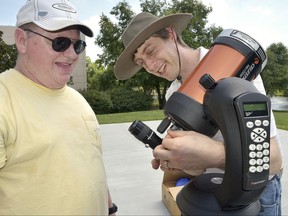 FILE - In this June 29, 2017 file photo, David Chrismon, left, a member of Guilford Technical Community College's student astronomy club, the Stellar Society, watches as Steve Desch, an astronomy instructor, sets up a telescope in Jamestown, N.C., that the group will use on their trip to Newberry, S.C. to observe a solar eclipse on Aug. 21. (Laura Greene/The High Point Enterprise via AP)