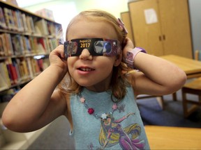 In this Wednesday, Aug. 2, 2017 file photo, Emmalyn Johnson, 3, tries on her free pair of eclipse glasses at Mauney Memorial Library in Kings Mountain, N.C.