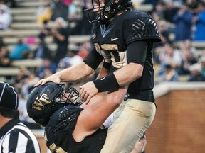 Wake Forest senior quarterback John Wolford (10) is congratulated by offensive lineman Ryan Anderson (70) after running in a touchdown during an NCAA college football game against Presbyterian, Thursday, Aug. 31, 2017, in Winston-Salem, N.C. (Andrew Dye/The Winston-Salem Journal via AP)