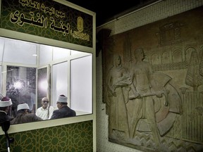 FILE - In this Tuesday, July 25, 2017, file photo Al-Azhar clerics wait to answer commuters questions inside a Fatwa Kiosk, at the Al Shohada'a metro station, in Cairo, Egypt. Egypt's Al-Azhar institute, the Sunni Muslim world's foremost religious institution, has set up a booth in a Cairo subway station with clerics offering fatwas, or religious advice, to commuters. (AP Photo/Nariman El-Mofty, File)