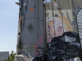 A mural resembling the work of elusive artist Banksy depicts U.S. President Donald Trump kissing an Israeli army watchtower, part of Israel's West Bank separation barrier in the West Bank city of Bethlehem, Friday, Aug. 4, 2017. (AP Photo/Nasser Nasser)