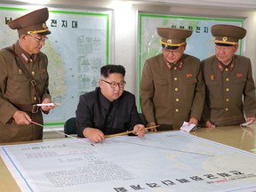 In this Aug. 14, 2017, photo distributed Tuesday, Aug. 15, 2017, by the North Korean government, North Korean leader Kim Jong Un, center,  talks with military commanders during his visit to Korean People's Army's Strategic Forces in North Korea