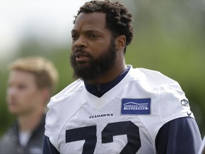 FILE - In this June 13, 2017, file photo, Seattle Seahawks defensive end Michael Bennett walks off the field following NFL football practice in Renton, Wash. Bennett says he will sit during the national anthem this season to protest social injustice and segregation. Bennett sat on the visiting bench during "The Star-Spangled Banner" on Sunday, Aug. 13, 2017, before the Seahawks' preseason opener against the Los Angeles Chargers, a decision he made prior to protests by white supremacists at the University of Virginia over the weekend. But what happened in Charlottesville, Virginia, including the death of a young woman when she was struck by a car deliberately driven into a group of counter-protesters on Saturday, solidified Bennett's decision. (AP Photo/Ted S. Warren, File)