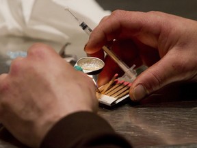 FILE - In this Wednesday, May 11, 2011, file photo, a man prepares heroin he bought on the street to be injected at the Insite safe injection clinic in Vancouver, British Columbia, Canada. The facility is promoted by its founders as a safe, humane facility for drug abusers. A report released Tuesday, Aug. 8, 2017, in the American Journal of Preventive Medicine revealed that a safe haven for drug users to inject themselves with heroin and other drugs has been quietly operating in the United States for the past three years. Researchers didn't disclose the location of the site. (Darryl Dyck/The Canadian Press via AP, File)