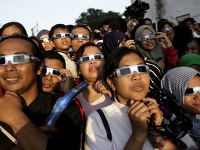 In this Wednesday, March 9, 2016 file photo, people wearing protective glasses look up at the sun to watch a solar eclipse in Jakarta, Indonesia