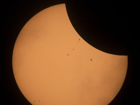 The International Space Station is seen in silhouette as it transits the sun during a partial solar eclipse, Monday, Aug. 21, 2017, near Banner, Wyo. (Joel Kowsky/NASA via AP)