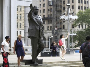 FILE - In this Wednesday, Aug. 10, 2016, file photo, people walk near a statue of late Philadelphia Mayor Frank Rizzo, who also served as the city's police commissioner, on Thomas Paine Plaza outside the Municipal Services Building in Philadelphia. Democratic Mayor Jim Kenney said Tuesday, Aug. 15, 2017, that the city should discuss the future of the Rizzo statue after reports of possible vandalism and a call for its removal from a city councilwoman. (AP Photo/Dake Kang, File)