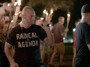 FILE - In this Friday, Aug. 11, 2017, file image made from a video provided by Vice News Tonight, Christopher Cantwell attends a white nationalist rally in Charlottesville, Va. On Wednesday, Aug. 23, Cantwell, a white nationalist, turned himself in to face three felony charges in Virginia, authorities said. Cantwell was wanted by University of Virginia police on two counts of the illegal use of tear gas or other gases and one count of malicious bodily injury with a "caustic substance," explosive or fire. (Vice News Tonight via AP, File)