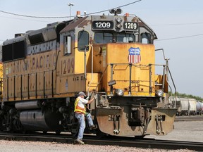 FILE - In this Thursday, July 20, 2017, file photo, a Union Pacific employee climbs on board a locomotive in a rail yard in Council Bluffs, Iowa. Union Pacific is laying off 500 managers and 250 other workers to reduce costs and eliminate about 8 percent of the railroad's managers. The railroad told the affected workers Wednesday, Aug. 16, 2017, that their jobs will be eliminated by mid-September. (AP Photo/Nati Harnik, File)