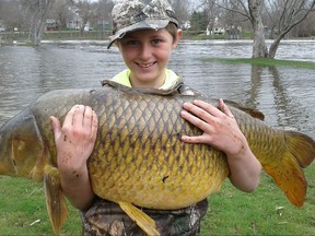 This April 22, 2017 photo released by John Stokes shows Stokes' son Chase, then 10, holding a giant carp, weighing 33.25 pounds, in Ferrisburgh, Vt. The Vermont Fish & Wildlife Department made the record official a few weeks ago, stating that the fish was a quarter-pound bigger than the previous record holder. (John Stokes via AP)