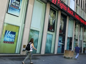 People pass the News Corporation headquarters building and Fox News studios in New York, Tuesday, Aug. 1, 2017. Fox contributor Rod Wheeler, who worked on the Seth Rich case, claims Fox News fabricated quotes implicating the murdered Democratic National Committee staffer in the Wikileaks scandal and that President Donald Trump pressured Fox to publish the story. He sued Fox for defamation on Tuesday. (AP Photo/Richard Drew)
