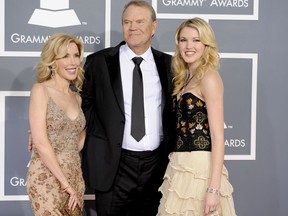 FILE - In this Feb. 12, 2012 file photo, Glen Campbell, center, Kim Woolen, left, and Ashley Campbell arrive at the 54th annual Grammy Awards in Los Angeles. Campbell, the grinning, high-pitched entertainer who had such hits as "Rhinestone Cowboy" and spanned country, pop, television and movies, died Tuesday, Aug. 8, 2017. He was 81. Campbell announced in June 2011 that he had been diagnosed with Alzheimer's disease. (AP Photo/Chris Pizzello, File)