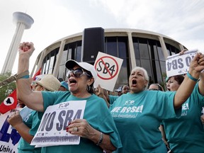 FILE - In this June 26, 2017, file photo, Lydia Balderas, left, and Merced Leyua, right, join others as they protest against a new sanctuary cities bill outside the federal courthouse in San Antonio. A federal judge late Wednesday, Aug. 30, temporarily blocked most of Texas' tough new "sanctuary cities" law that would have let police officers ask people during routine stops whether they're in the U.S. legally and threatened sheriffs will jail time for not cooperating with federal immigration authorities. The law, known as Senate Bill 4, had been cheered by President Donald Trump's administration and was set to take effect Friday. (AP Photo/Eric Gay, File)