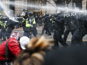 FILE- In this Jan. 20, 2017, file photo, police fire pepper spray at protestors during a demonstration in downtown Washington after the inauguration of President Donald Trump. A District of Columbia Superior Court ruled Thursday, Aug. 24, that an internet hosting company must turn over records for a website that the government alleges was used to plan violent protests on the day of President Donald Trump's inauguration. (AP Photo/John Minchillo, File)