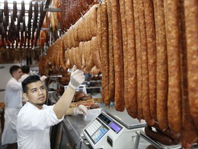 In this Thursday, July 20, 2017 photo, homemade sausages and other cured meats hang above the counter at Muncan Food Corp. in the Astoria, Queens neighborhood of New York. Founded in 1978 by brothers Tima and John Muncan, immigrants from the former Yugoslavia, the shop is now run by one of the brothers' grandsons, and is known for it's many sausage, bacon and prosciutto varieties. The Travel Channel's "Bizarre Foods" host Andrew Zimmern, a four-time James Beard award winning chef, likes to come to Muncan and similar lesser-known places when the cameras aren't rolling. Zimmern will feature his personal favorites, places he goes when the cameras aren't rolling, in a new show called "The Zimmern List," debuting in early 2018. (AP Photo/Kathy Willens)