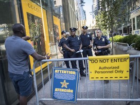 In this Thursday, Aug. 10, 2017 photo, police officers give a pedestrian directions while standing guard outside Trump Tower in New York.  Donald Trump plans to come home to Trump Tower for a few days starting Sunday, the first time since his inauguration. New York City police are planning a slight security clampdown in the area around the skyscraper for the duration of his visit. (AP Photo/Mary Altaffer)