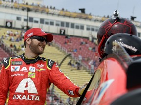 Dale Earnhardt Jr. smiles while talking with a crew member before qualifying for the NASCAR Cup Series auto race, Sunday, Aug. 6, 2017, in Watkins Glen, N.Y. (AP Photo/Matt Slocum)