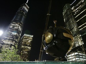A section of the Koenig Sphere, a 25-ton bronze sphere damaged by the collapsing World Trade Center is lifted by crane into Liberty Park near One World Trade Center on Wednesday, Aug. 16, 2017, in New York. Plans were approved last year to move the sculpture from its temporary place in Battery Park at Manhattan's southern tip. The sphere once stood between the trade center's two towers. (AP Photo Peter Morgan)