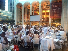 Guests clad in white sit down to a pop-up dinner at New York's Lincoln Center, Tuesday, Aug. 22, 2017. The event, known as Diner en Blanc, French for Dinner in White, is an annual foodie tradition and began in Paris 29 years ago. (AP Photo/Julie Walker)