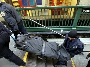 In this Jan. 22, 2013 file photo, a police officer and medical examiner personnel carry a body out of the Times Square subway station in New York after witnesses told police that the man who died jumped into the path of an oncoming train. It's a largely overlooked but gory reality of the New York City subway system: When someone kills themselves by jumping in front of a train, police need to find a place to put the mutilated body until a medical examiner truck arrives. Sometimes, transit workers say, that place is their break room or bathrooms, and some say they have been traumatized by unexpectedly coming upon a stowed body.