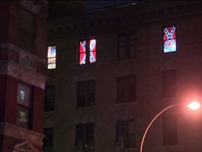 This Aug. 17, 2017 image made from a video shows Confederate flags displayed in the seventh-floor windows of an apartment in the East Village neighborhood of New York. The flags had been there for over a year, but after an Aug. 12 white nationalist rally to preserve a Confederate statue in Charlottesville, Vaa, spiraled into violence the flags were met with hurled rocks, a punched-out window, a tarp hung over them and legal action before being removed. (PIX11 News via AP)