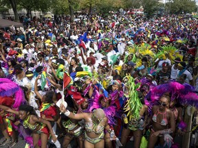 FILE - In a Monday, Sept. 5, 2016 file photo, participants blend in to the crowd of spectators as they march during the West Indian Day Parade in the Brooklyn borough of New York. City officials shifted the start time of the pre-dawn festival celebrating Caribbean culture and are taking other security precautions to stem violence ahead of the West Indian Day Parade this year. J'ouvert usually begins at 4 a.m. on Labor Day on the streets of Brooklyn but will start this year at 6 a.m. Barriers will be placed along the route. Revelers will have to pass through metal detectors, and no alcohol or backpacks will be allowed. Police say the precautions are similar to security during New Year's Eve in Times Square. (AP Photo/Craig Ruttle, File)