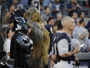 Characters dressed as Darth Vader and Chewbacca from the movie "Star Wars" stand on the field during the playing of the national anthem before a baseball game between the New York Yankees and the Seattle Mariners on Friday, Aug. 25, 2017, in New York. (AP Photo/Frank Franklin II)