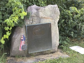 In this August 2017 photo an American flag is displayed next to a marker in remembrance of Confederate Gen. Robert E. Lee and the Dixie Highway, in Franklin, Ohio. The roadside marker honoring the Confederate general has swept the city of Franklin into the heated conflict over such monuments. The movement in recent years to remove Confederate monuments and flags from public places as symbols of national division and black oppression has accelerated since deadly violence this month in Virginia. The marker was recently removed overnight by officials concerned about violent protests or its destruction. (Ed Richter /The Journal-News via AP)