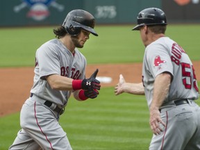 Boston Red Sox' Andrew Benintendi is congratulated by Boston Red Sox' third base coach Brian Butterfield after hitting a two-run home run off Cleveland Indians starting pitcher Mike Clevinger during the first inning of a baseball game in Cleveland, Monday Aug. 21, 2017. (AP Photo/Phil Long)