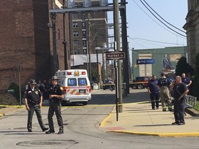 Steubenville, Ohio, police officers, Jefferson County Sheriff's Department deputies and other investigators work following an ambush-style shooting of Jefferson County Judge Joseph Bruzzese Jr. on Monday, Aug. 21, 2017, on the Court Street side of the Jefferson County Courthouse in Steubenville, Ohio. Bruzzese was shot and wounded Monday morning as he walked toward his county's courthouse, and a suspect was killed after a probation officer returned fire, officials said. (Mark Law/Herald-Star via AP)