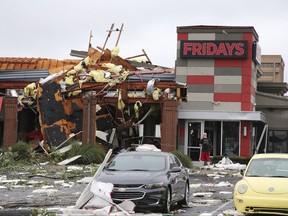 A man stands outside a Fridays restaurant after a storm moved through the area in Tulsa, Okla., Sunday, Aug. 6, 2017. A possible tornado struck near midtown Tulsa and causing power outages and roof damage to businesses. (Tom Gilbert/Tulsa World via AP)