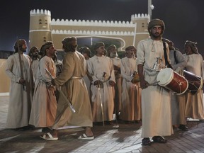 FILE -- In this July 31, 2017 file photo, a group of dancers wait to perform a sword-dance during the annual summer monsoon festival in Salalah, Oman. The 60-day festival draws about 50,000 people nightly for dagger-dance competitions, musical performances and Sufi exorcisms performed in celebration of Oman's cultural diversity of Arab, African, and Asian roots. (AP Photo/Sam McNeil, File)