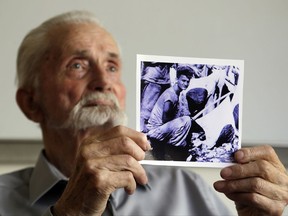 In this Monday, Aug. 7, 2017 photo, WWII veteran Marvin Strombo holds up a photo of himself taken during the battle on Saipan with him holding a captured sword and flag in Portland, Ore. Strombo recovered the flag from a dead Japanese soldier in the Pacific more than 70 years ago and now, at age 93, will return the flag to the Japanese man's surviving siblings. (AP Photo/Don Ryan)