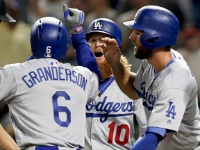Los Angeles Dodgers' Curtis Granderson (6) is greeted by teammates, Justin Turner (10) and Chris Taylor, right, after driving them and Corey Seager in with a grand-slam home run off Pittsburgh Pirates starting pitcher Gerrit Cole in the seventh inning of a baseball game, Monday, Aug. 21, 2017, in Pittsburgh. (AP Photo/Keith Srakocic)